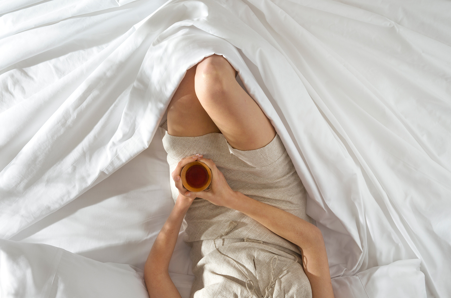 Woman drinking tea while lounging in bed