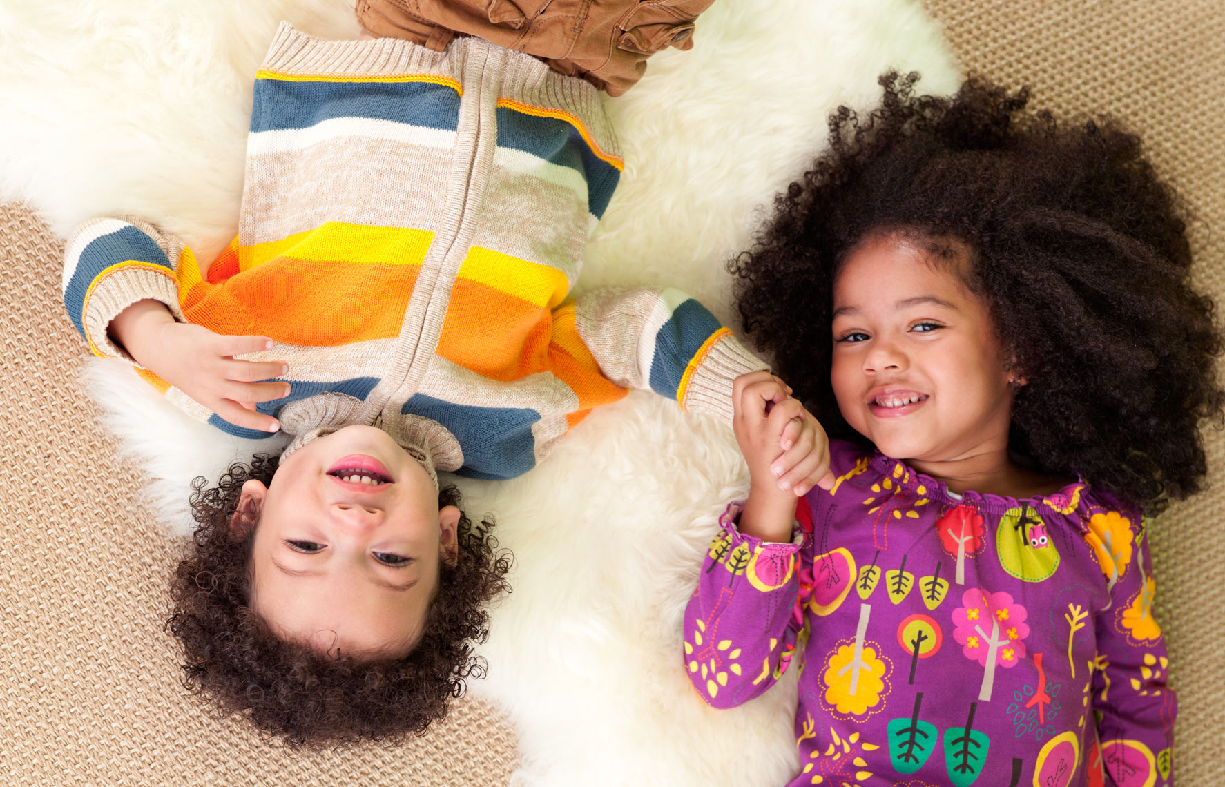 African-American brother and sister laying next to each other holding hands