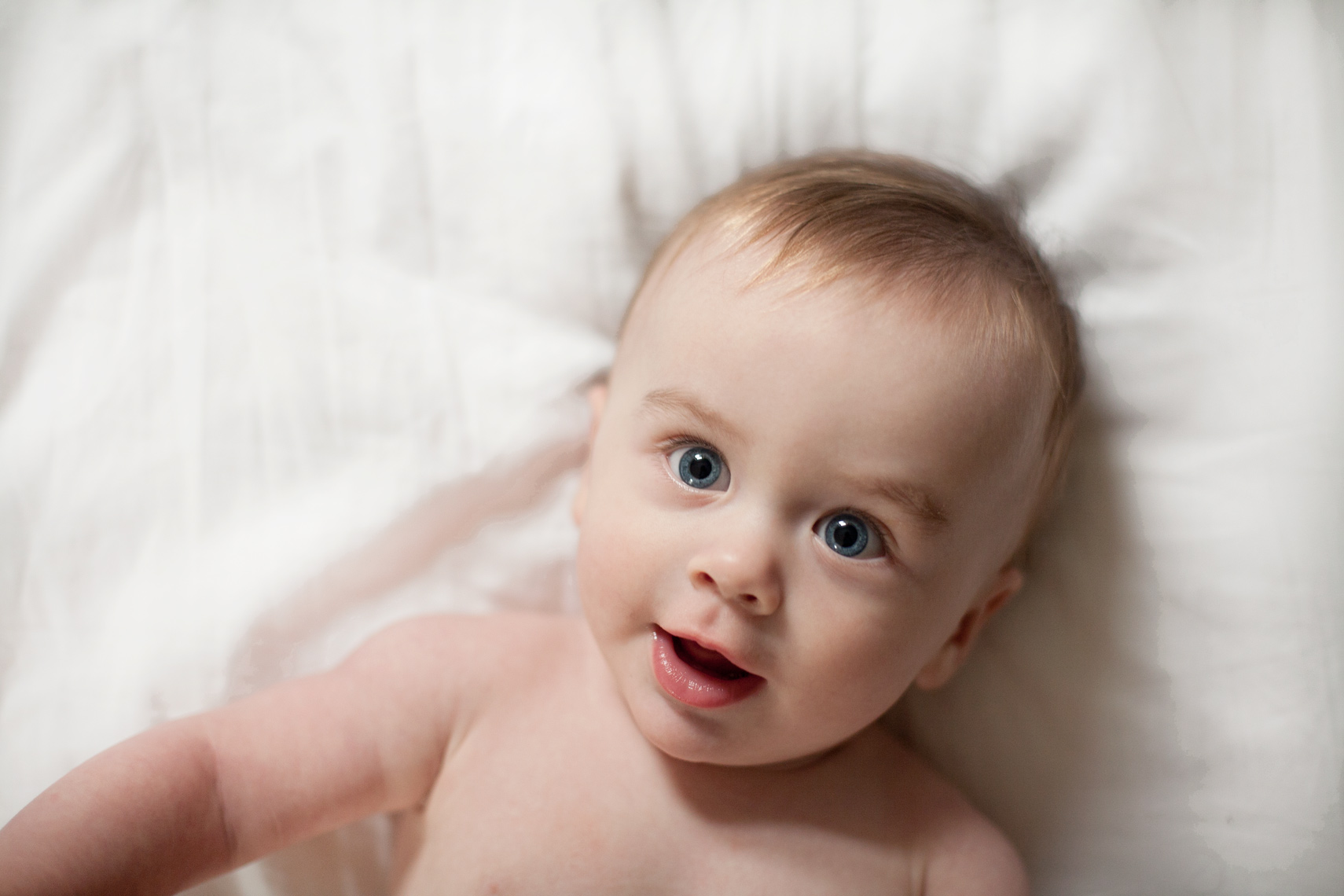 baby on bed with blue eyes smiling