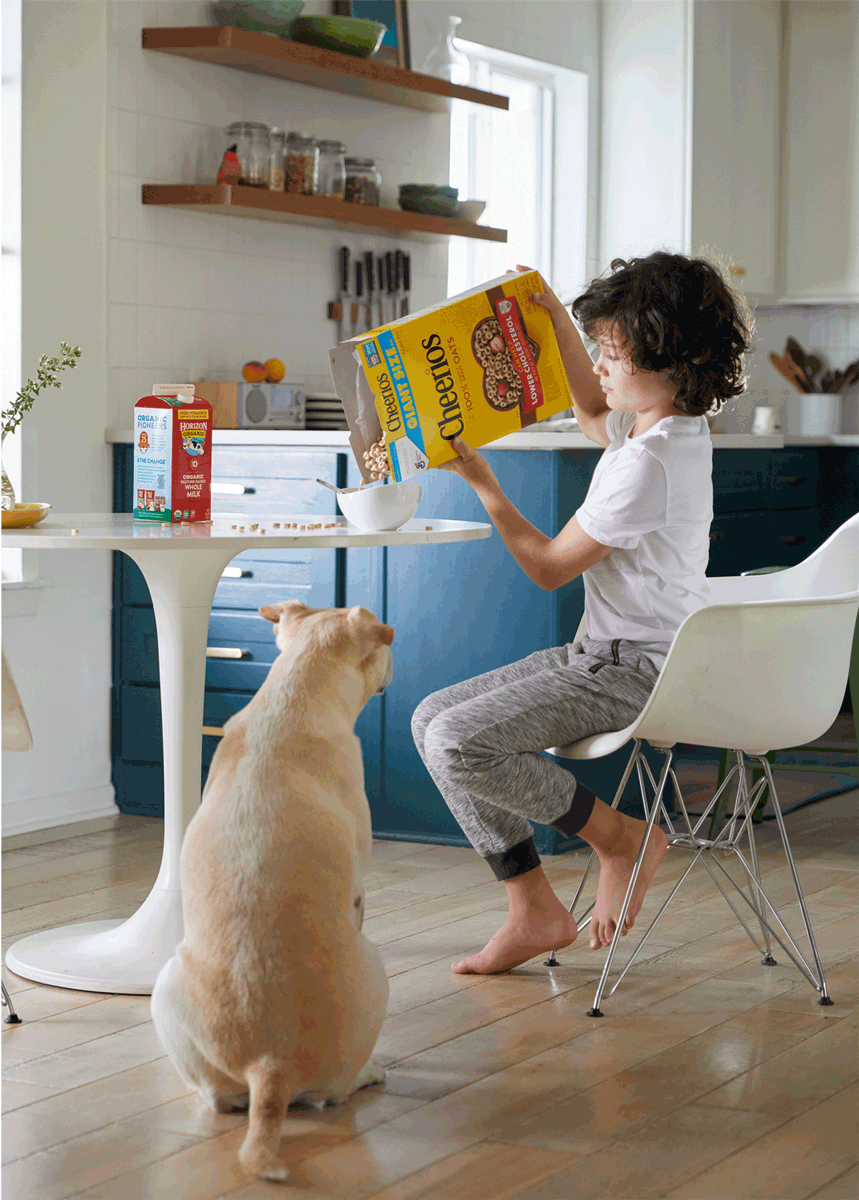 Tween eating cheerios with his dog by lifestyle photographer Buff Strickland