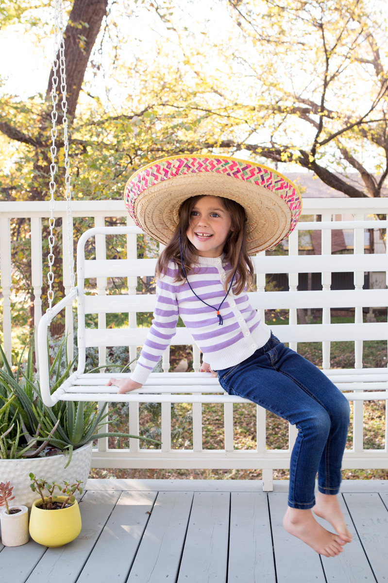 little girl in sombrero on porch swing