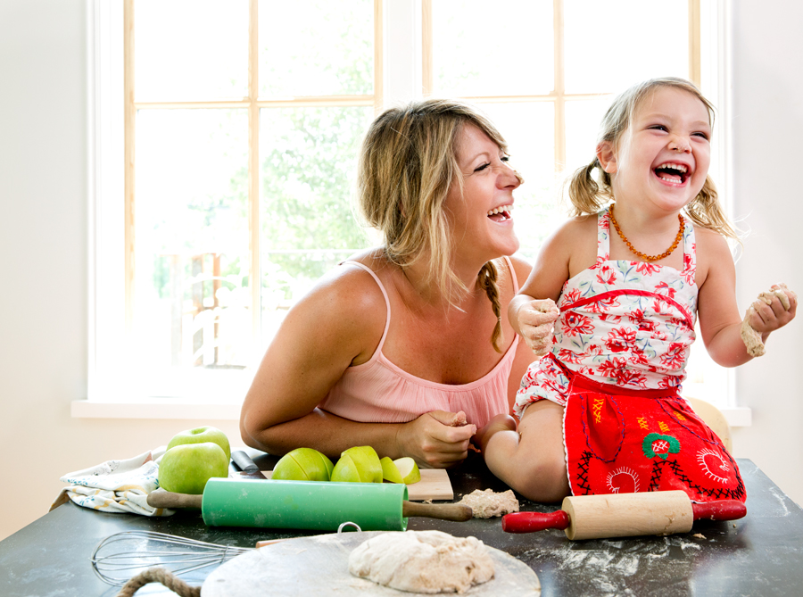 Mom and daughter baking together with apples and laughing kitchen table