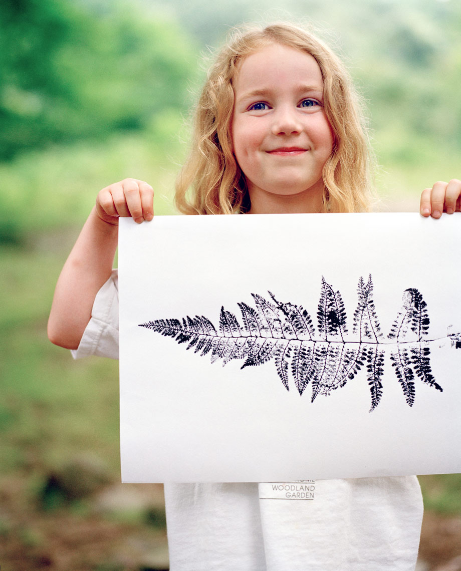girl holding a leaf print on white paper long blond hair