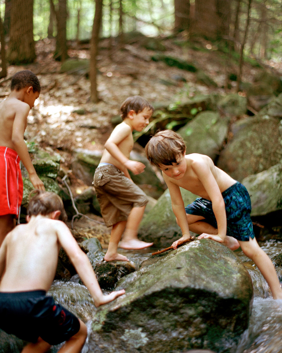 kids playing on rocks in creek in summer