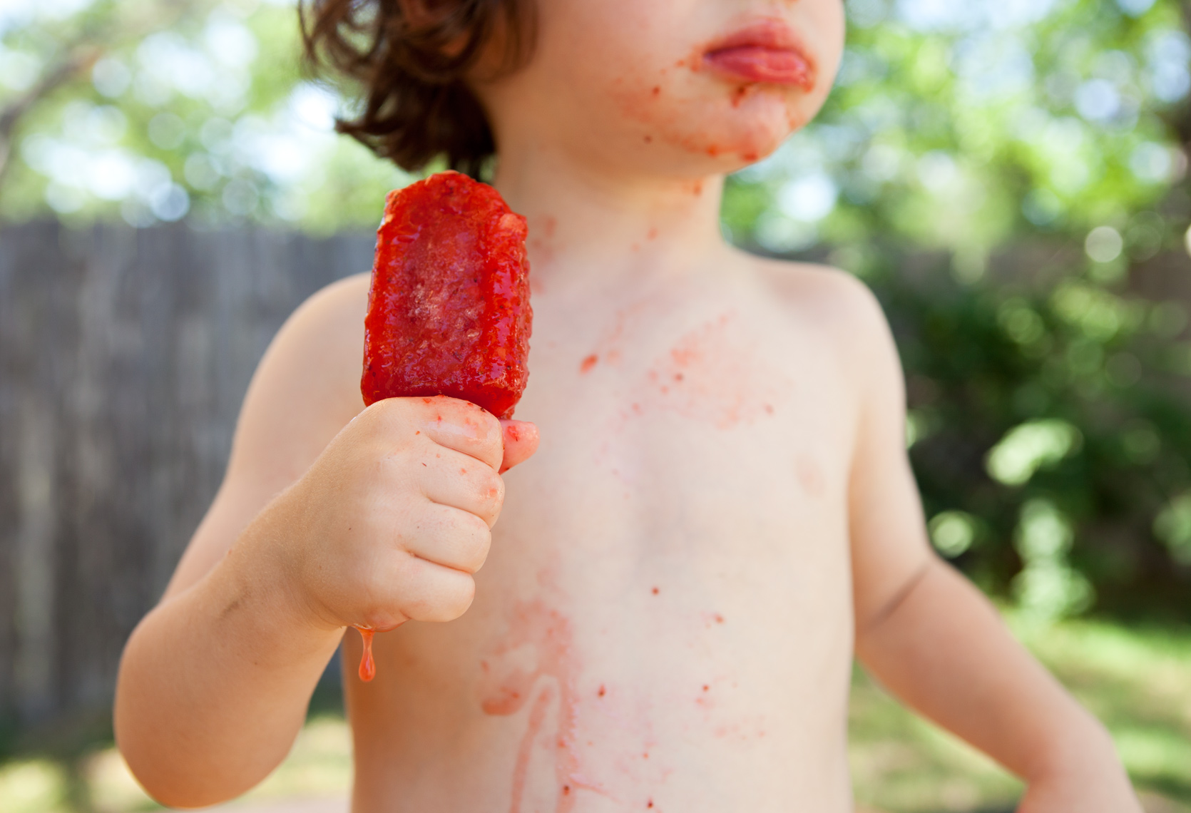 kid eating red popsicle  melting on a hot summer day