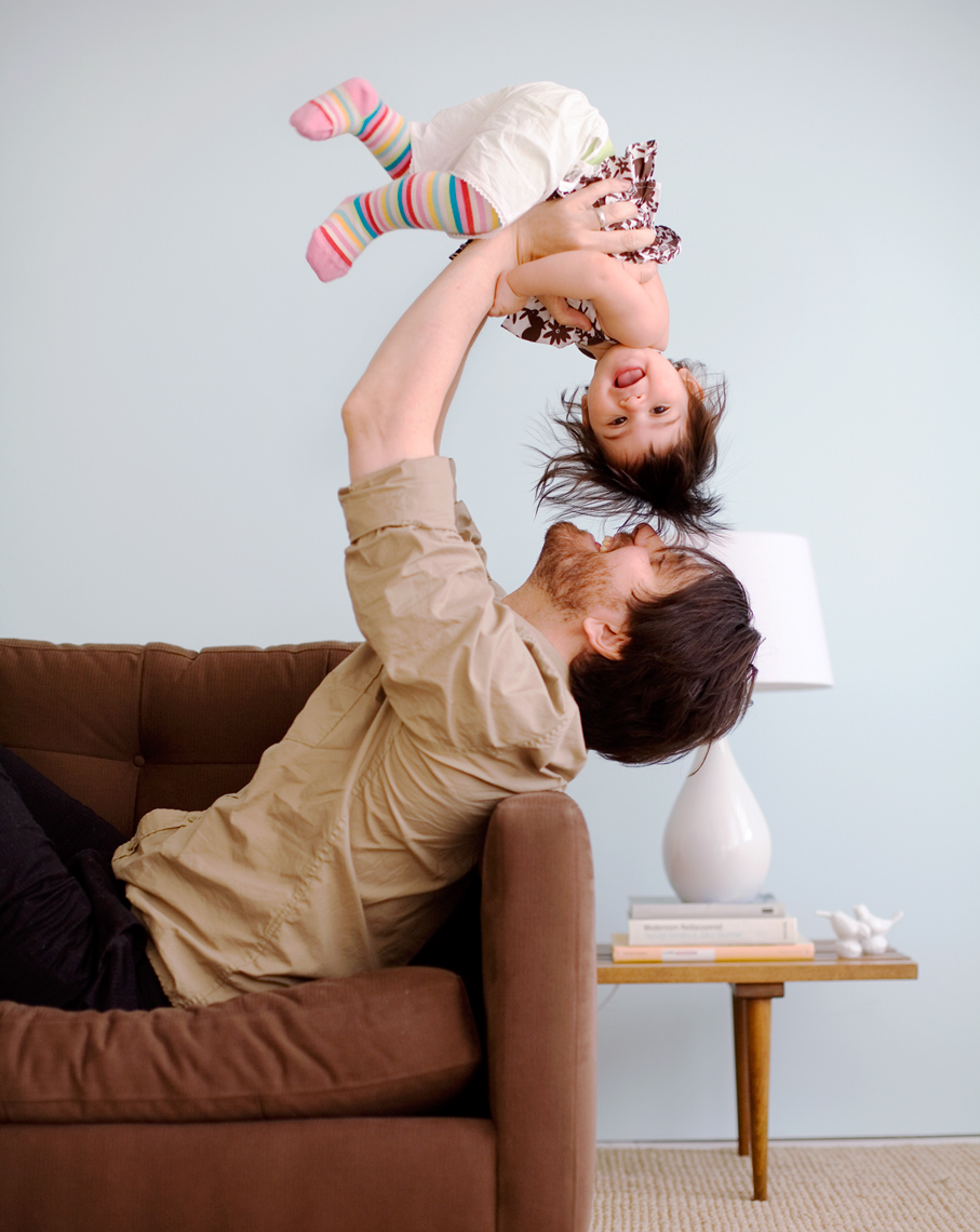 Dad picking little girl up over his head with pink stripes by kid photographer Buff Strickland