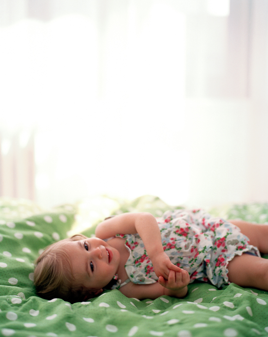 young girl on bed in floral dress laughing